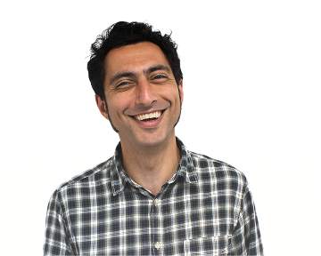A cheerful man smiles wearing a checked pattern shirt
